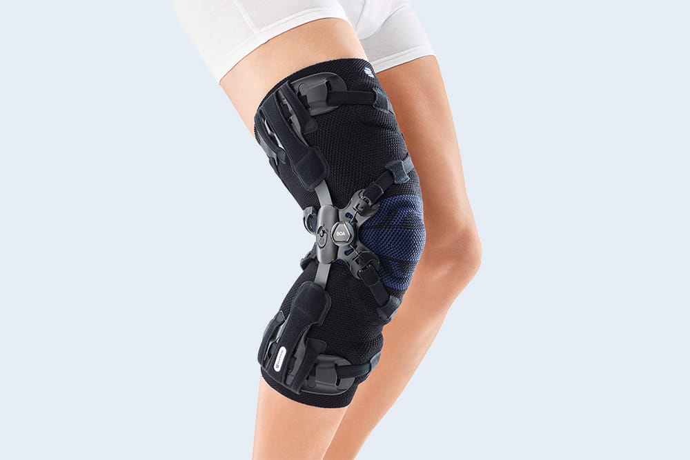 A close-up of the Genutrain OA, a leg orthosis in blue, applied to the knee.