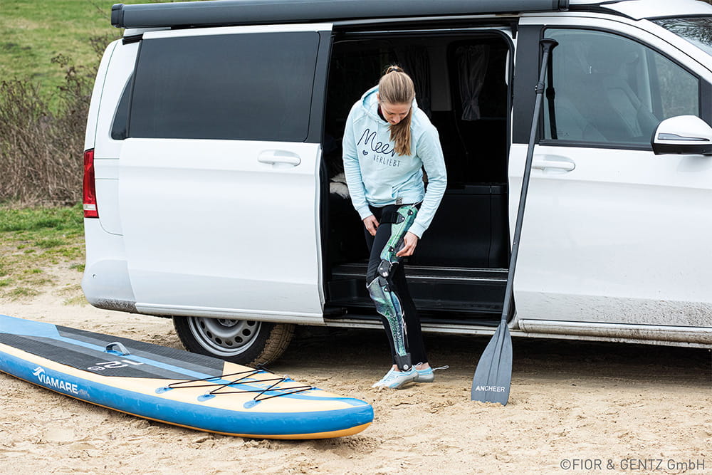 A woman with a full-leg orthosis prepares for stand-up paddling.