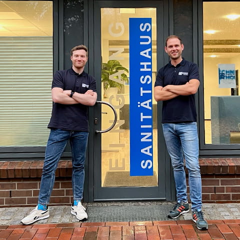 Florian Krassel and Maximilian Normann stand proudly in front of the shop door.