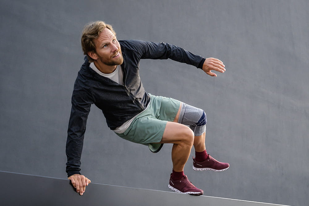 A man jumps off a ledge wearing a knee brace.