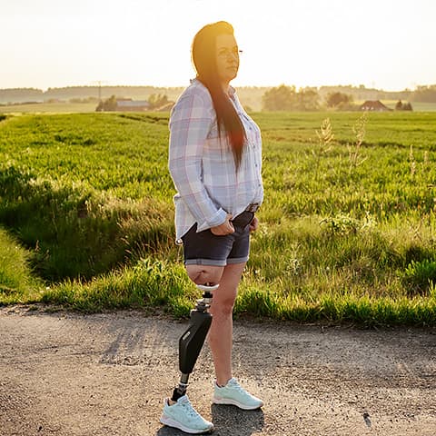 Annika is standing in the backdrop in nature. She is wearing her endo-exo prosthesis.