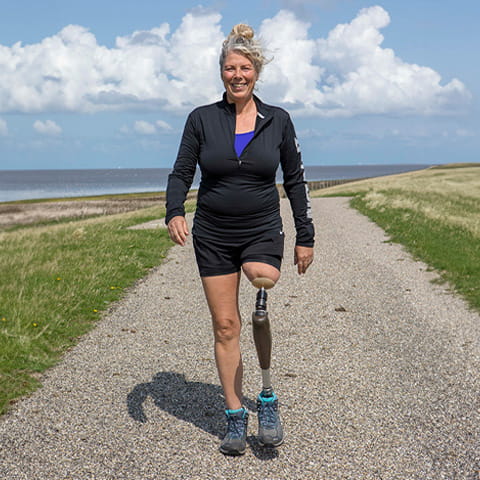 Eine Frau mit Endo-Exo-Prothese ist an der Küste beim Wandern zu sehen.