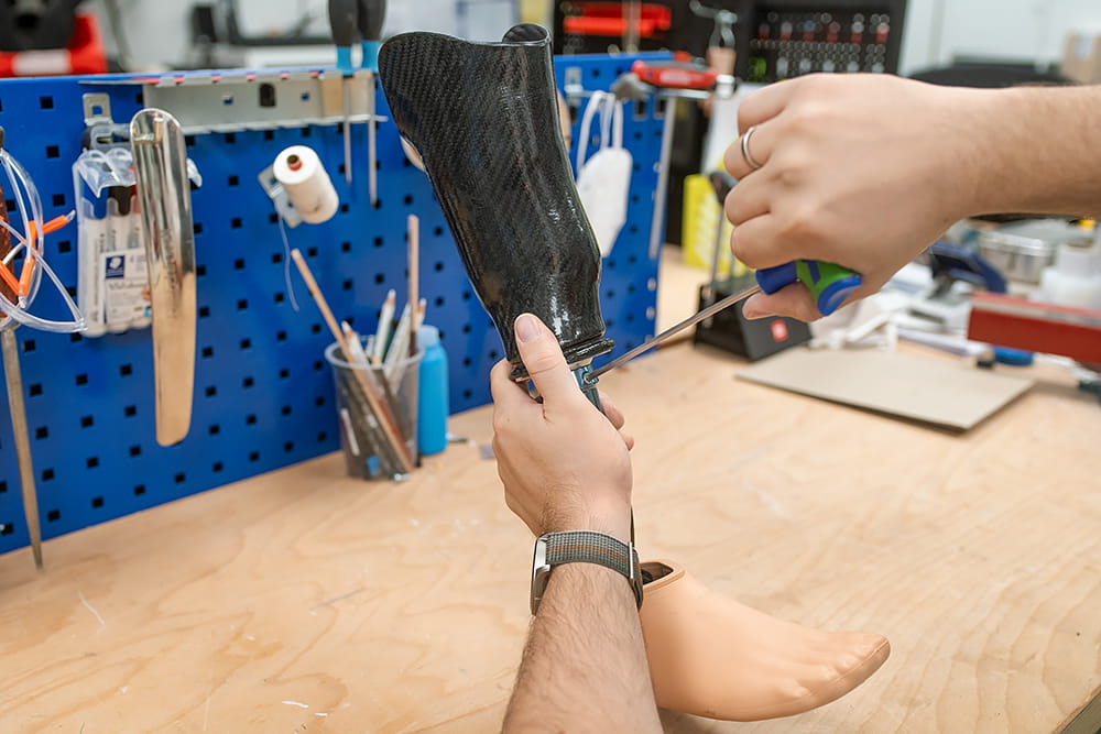 Ein Mitarbeiter der TOH arbeitet an einer Beinprothese.