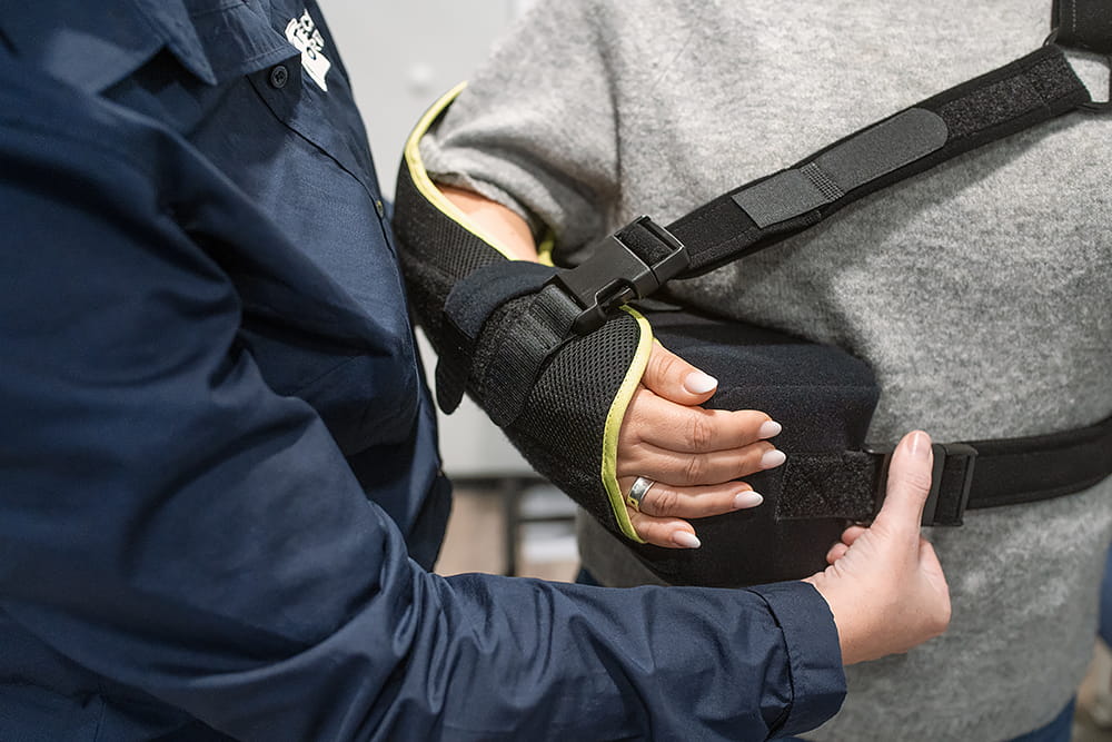 Eine Mitarbeiterin des Sanitätshauses legt einer Kunin eine Armorthese an.