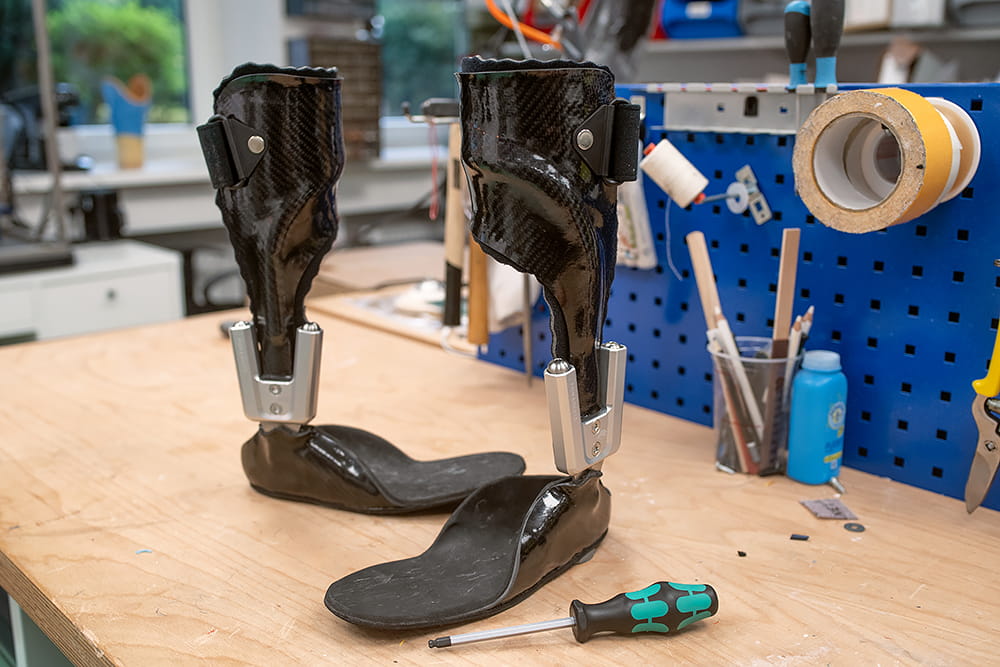 Ein Blick auf einen arbeitstisch ind er Werksatt auf dem zwei Beinorthesen stehen.