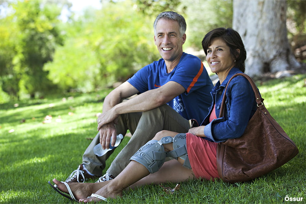 Ein Paar sitzt im PArk und die Dame trägt eine Beinorthese.